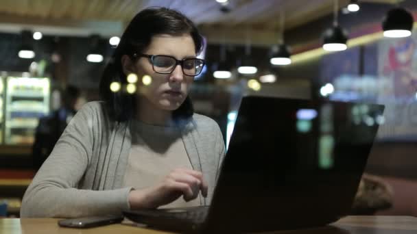 Hon arbetar med datorer i ett trevligt Cafe, hon sitter vid ett bord vid fönstret. — Stockvideo