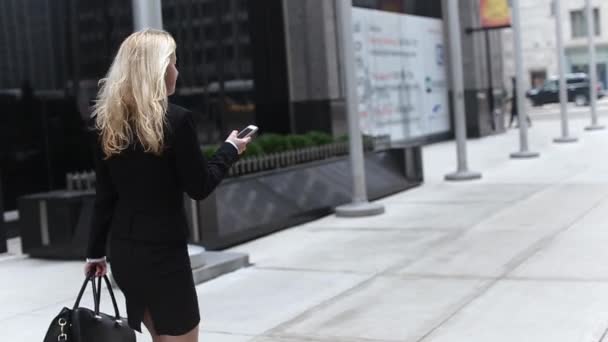 Atractiva rubia mujer de negocios usando el viajero de Smartphone en la ciudad — Vídeos de Stock