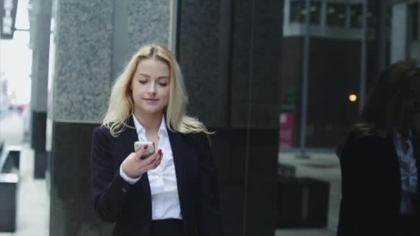 Mujer de negocios bastante joven hablando por teléfono contra el complejo de edificios de oficinas modernos . — Vídeos de Stock