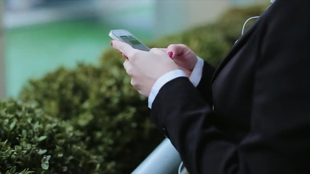 Joven mujer de negocios caminando y mensajes de texto en el teléfono inteligente en la ciudad — Vídeos de Stock