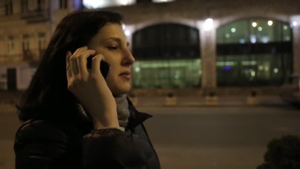 Дівчина ходить по дорозі вночі біля магазинів телефонів — стокове відео