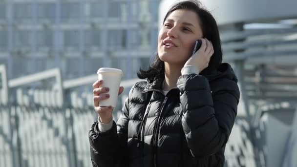 Fille avec café parler au téléphone. Fille dans une veste noire — Video