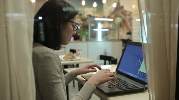 Ze werkt met de Computer, weergeven door het raam van een Cafe. — Stockvideo