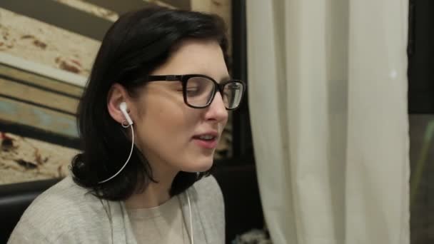Chica escuchando música y tomando café en un café — Vídeos de Stock