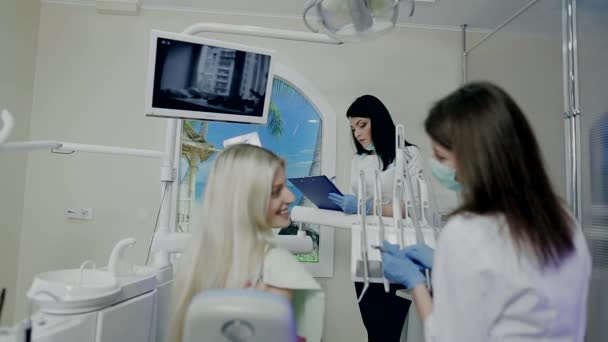 Assistente toma notas enquanto o médico exemplifica o paciente e sorrindo — Vídeo de Stock