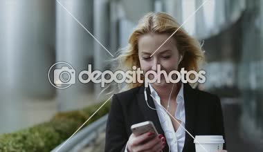 Telefon ve kahve el ve kulaklık ile başarılı ve güzel kız. Kız gökdelen de güzeldir