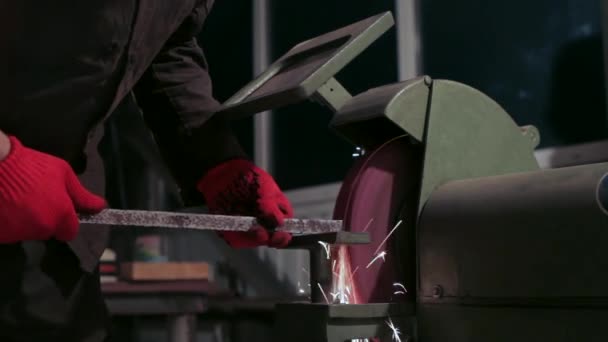 Master in Red Gloves Grinds Hardware. il fonctionne avec une machine verte qui a un disque rouge, il tourne. L'homme travaille dans un atelier et il y a beaucoup d'appareils . — Video