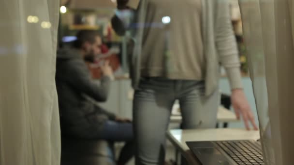 Sie arbeitet mit dem computer, blick durch das fenster eines cafés. — Stockvideo