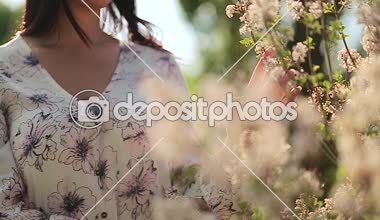 Güzel kız Bahçe üzerinde bir güneşli gün ve dokunuşlar çiçek ayakta