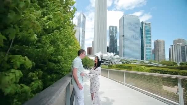 Hermosa pareja enamorada caminando en el puente junto a rascacielos en el centro de Chicago en un día soleado — Vídeos de Stock