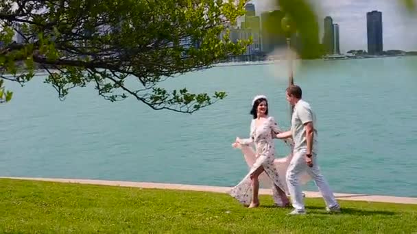 Влюбленная пара прогуливается по зеленой лавке на фоне Чикаго и поцелуев — стоковое видео