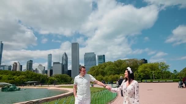 Hermosa pareja enamorada caminando en la fuente cerca de los rascacielos en el centro de Chicago en un día soleado — Vídeo de stock
