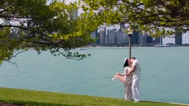 Piękna para zakochanych, chodzenie na zielony trawnik na tle Chicago i pocałunki — Wideo stockowe