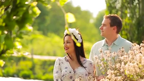 Älskande par i en botanisk trädgård på en solig dag omfamna — Stockvideo