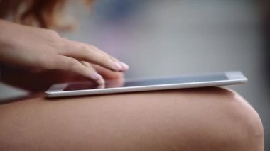 Bankta oturan ve onun Tablet dokunmadan uzun ve kıvırcık saçlı Petite kız