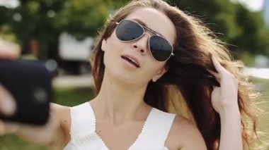 Güzel kız beyaz gömlek ve siyah güneş Selfies Gölü ve uzun binalar ile arka planda alarak