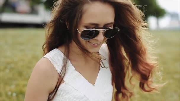 Atractiva sonrisa, hermosa chica en gafas de sol en el movimiento del día soleado . — Vídeos de Stock