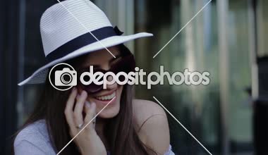 Şapka döner kapılar arka plan üzerinde telefonda konuşurken genç güzel gülümseyen kadın.