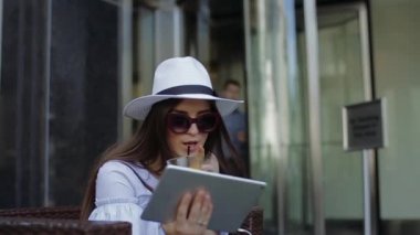 Çekici kadın sokak Cafe oturur ve içecekler portakal suyu.