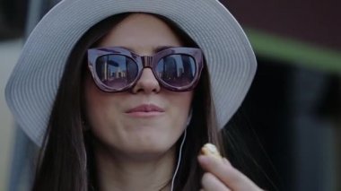 Şapka ve güneş gözlüğü gökdelenler yansıması ile gülümseyen, badem kraker ile kahve içmeye genç.