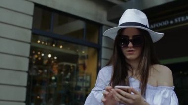 Genç kadın arama numarasına cep telefonu gülümseyerek oturan Cafe dışında açıktır.