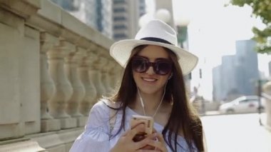 Şapka ve güneş gözlüğü genç kadın Video aramasý Smartphone üzerinden şehir merkezinde içinde yapar..
