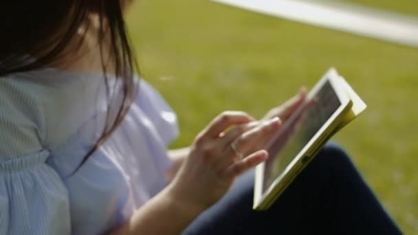 Přitažlivá mladá žena sedí v létě na trávě. — Stock video