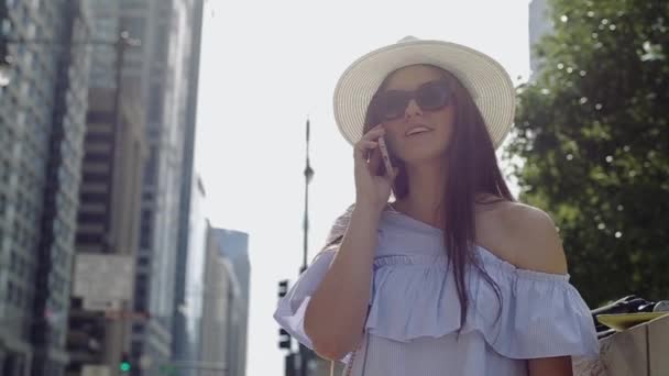 Stylová žena stojí na letní ulici obklopená vysokými budovami. — Stock video