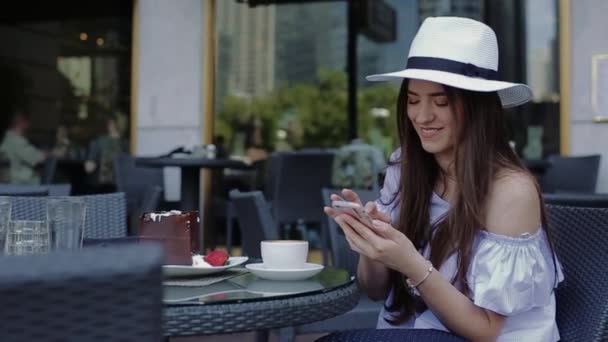 Mulher bonita senta-se na mesa de madeira no café de rua e bate-papos . — Vídeo de Stock