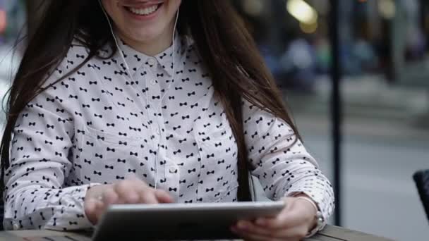 Cheerful Woman With Long Brown Hair Sits on Street et écoute de la musique . — Video