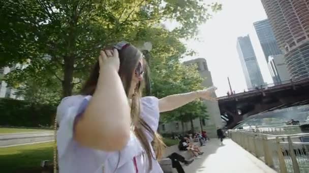 Jovem alegre Senta-se na grama no parque e ouve música . — Vídeo de Stock