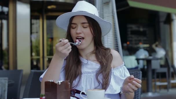 Joven y hermosa hembra está comiendo postre sentado fuera en el café — Vídeos de Stock