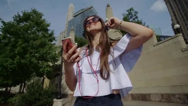 Mujer sonriente bailando de pie en la calle escuchando música — Vídeos de Stock