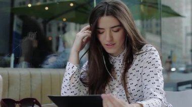 Sokak Cafe ve müzik dinler tabletten genç kadın oturur.
