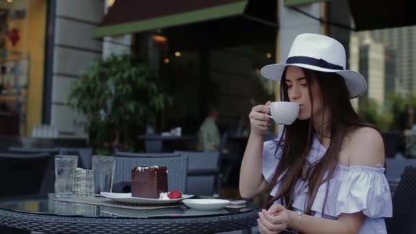 Jonge vrouwelijke is drinken koffie zitten buiten in Cafe of op terras. — Stockvideo