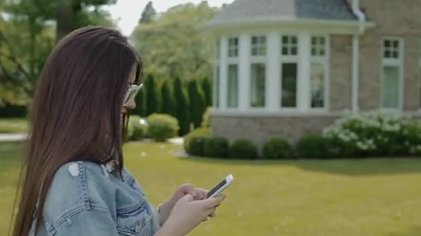 Mujer feliz camina en el parque y chats en el teléfono celular . — Vídeos de Stock