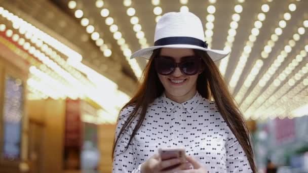 Νεαρά θηλυκά είναι μιλώντας σε κινητό τηλέφωνο στέκεται στο εμπορικό κέντρο αίθουσα χαμογελώντας. — Αρχείο Βίντεο