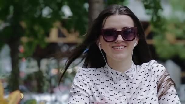 Молодая и красивая женщина сидит снаружи, размахивая волосами — стоковое видео