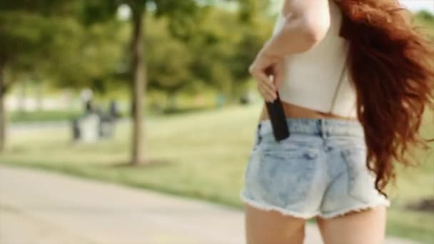 Belle fille caucasienne avec de longs cheveux bruns répond et parle par téléphone à Big Green Park — Video