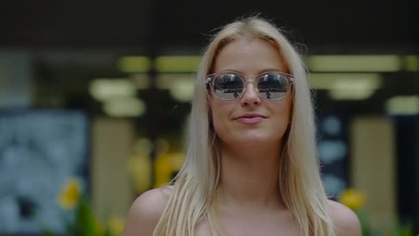 Jong blond meisje opstijgt zonnebril en glimlacht. — Stockvideo