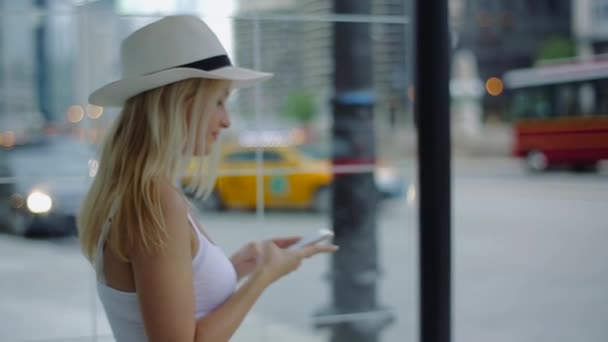 Mladá atraktivní blond dívka v bílé košili a Kapelyuhovitrymaye v rukou telefon a vytočí zprávy. — Stock video