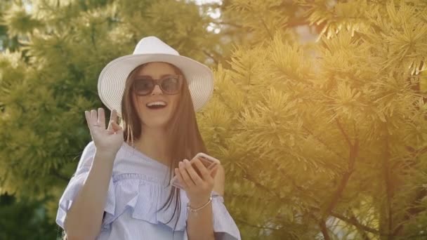 Mujer guapa se para cerca de Spinney gruesa verde y felizmente le da la mano . — Vídeo de stock