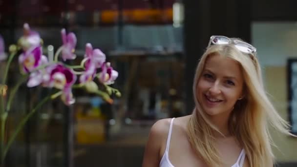 Une jeune fille avec un sourire va le long des fleurs d'orchidée . — Video