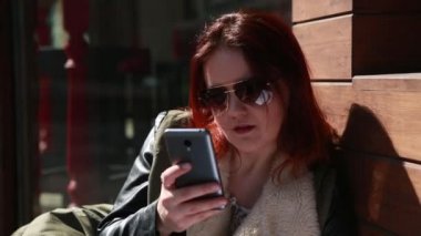 Kız deri ve güneş gözlüğü telefon Sigara içenler tarafından konuşuyor