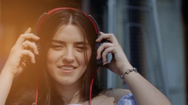 Mujer joven y hermosa se está poniendo grandes auriculares bailando — Vídeo de stock