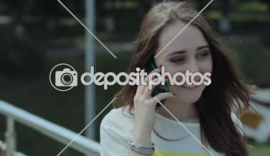 bir genç kız sevinçle bir cep telefonuyla konuşurken köprü aramalar, bahçedeki ayakta.