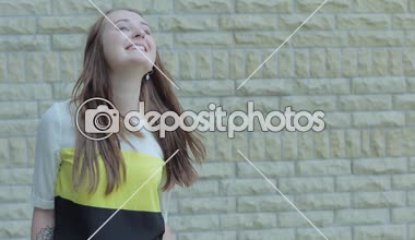 Genç çekici kız standları yakınındaki tuğla duvarlar ve gülümsüyor.