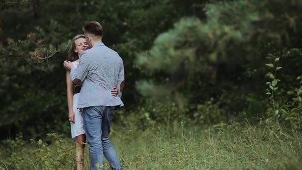 Una joven pareja enamorada pasean juntos por un hermoso bosque con su perro mascota. En cámara lenta . — Vídeo de stock