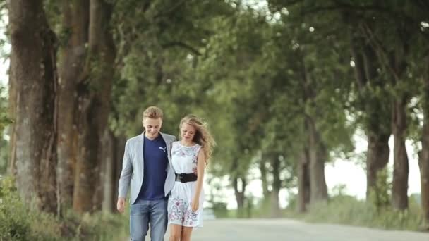 Una joven pareja enamorada pasean juntos por un hermoso bosque con su perro mascota. En cámara lenta . — Vídeos de Stock