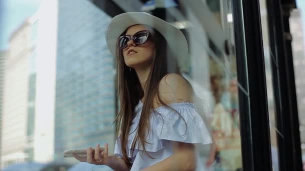 Joven mujer inteligente se para dentro cerca de la ventana y mira al cielo . — Vídeo de stock